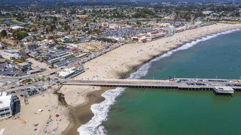 A long pier stretching into a bay next to a seaside amusement park in Santa Cruz, California.