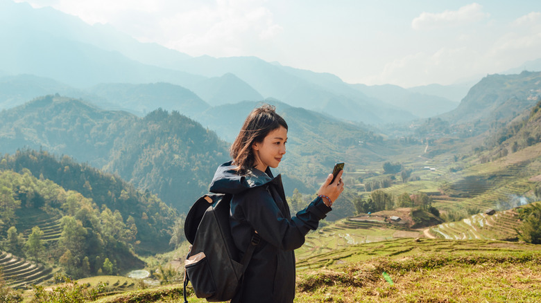 Woman on a hiking trail looking at her cell phone