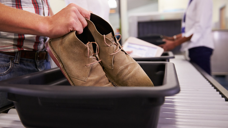 A man putting shoes in an airport security bin