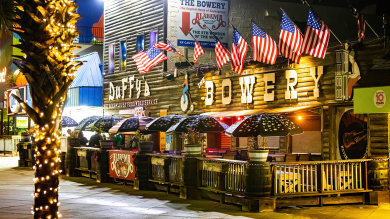 The front of The Bowery in Myrtle Beach with American flags, front patio, and umbrellas