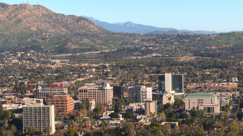 Aerial view of downtown Riverside with high-rise buildings and a lot of green hills and mountains.