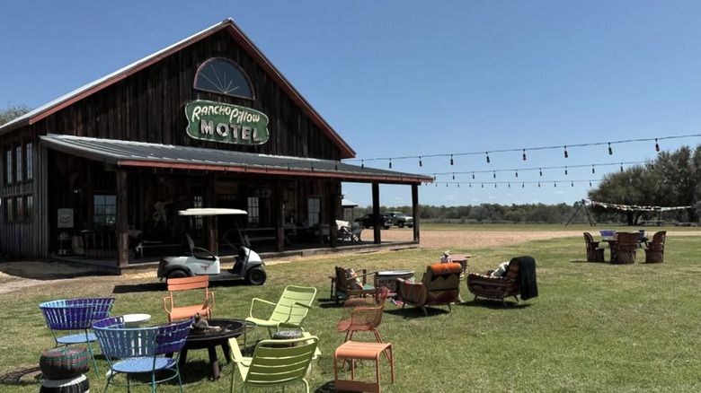 Chairs and firepits outside a wood building with a sign reading Rancho Pillow Motel, Texas
