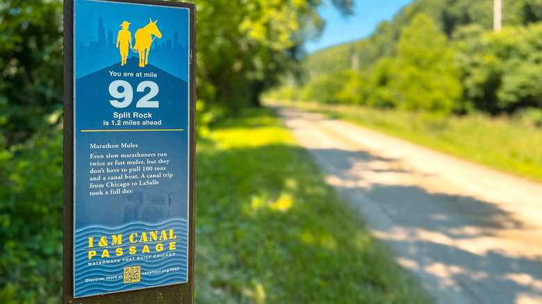A mile post stands next to a gravel section of the Grand Illinois Trail
