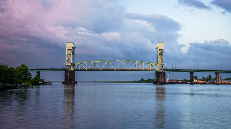 Cape Fear Memorial Bridge viewed from aboard a river boat on the water with purple sunset colors.