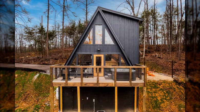 An black A-frame cabin by some woods