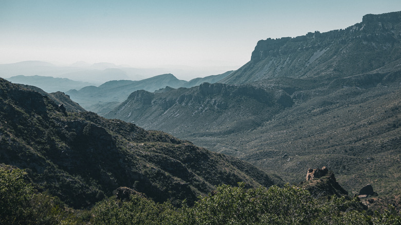 Mountaintop views of the shrub-covered mountains of Big Bend National Park on a hazy day