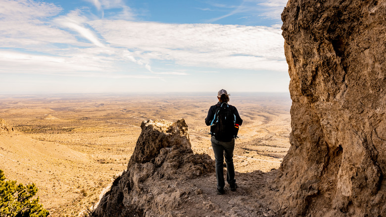 A woman looks out into the open valley below from the viewpoint on Guadalupe Peak Trail