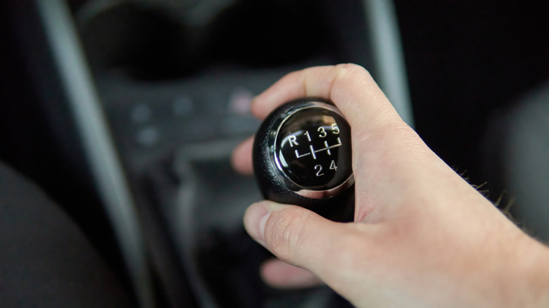 A hand moving a manual gearbox in a car