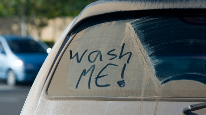 Dirty car window with "wash me" written on it
