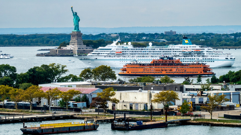 A Staten Island Ferry and a cruise ship pass the Statue of Liberty in NYC