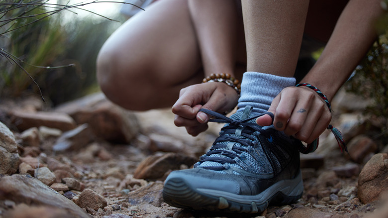 close up of kneeling person tying a trail runner-style hiking shoe