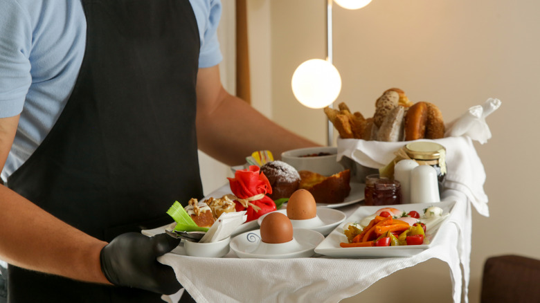 A hotel staff member bringing room service to a guest