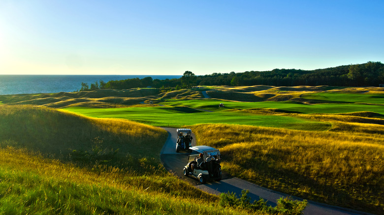 People riding golf carts on course at sunset