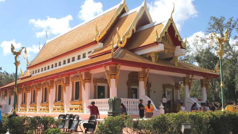 white and gold Thai temple with red trim and greenery