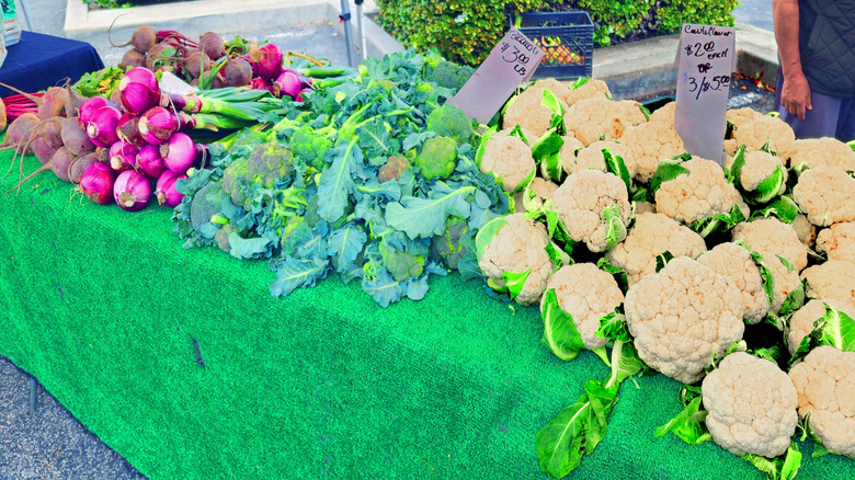 A table stacked with cauliflower, red onions, and beets at a farmers' market in Sacramento.