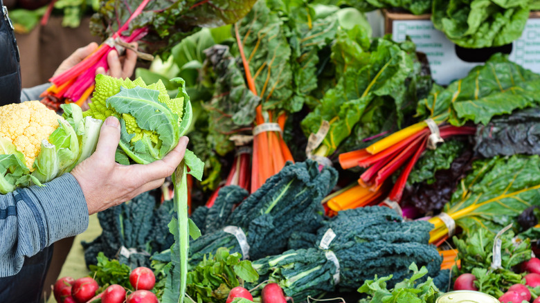 A shopper gathers cauliflower and other vegetable in his hands at the Sacramento Farmers' Market.