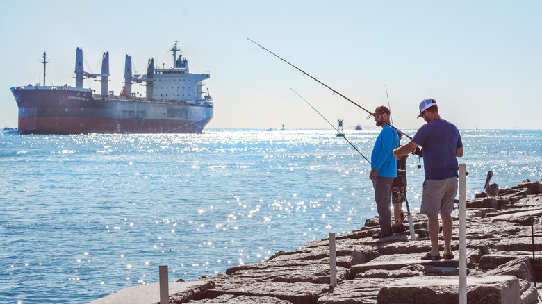 Fisherman on  the Port Aransas jetty with ship in distance