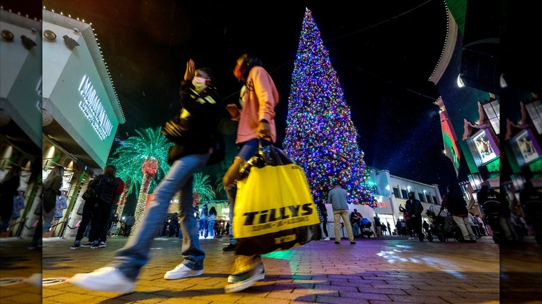People with shopping bags in front of the Christmas tree at the Citadel Outlets in Los Angeles