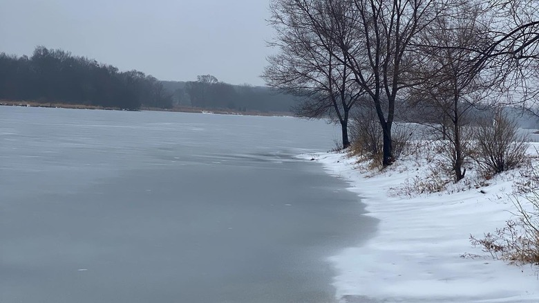Frozen water and snowy banks of Busse Lake in Elk Grove, Illinois
