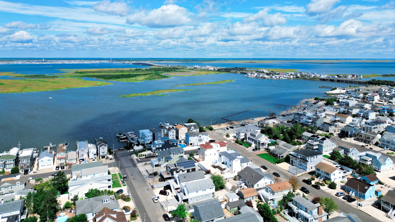 Aerial view of Ship Bottom, with residential streets in the foreground and blue water dotted with islands in the background, under a cloudy blue sky