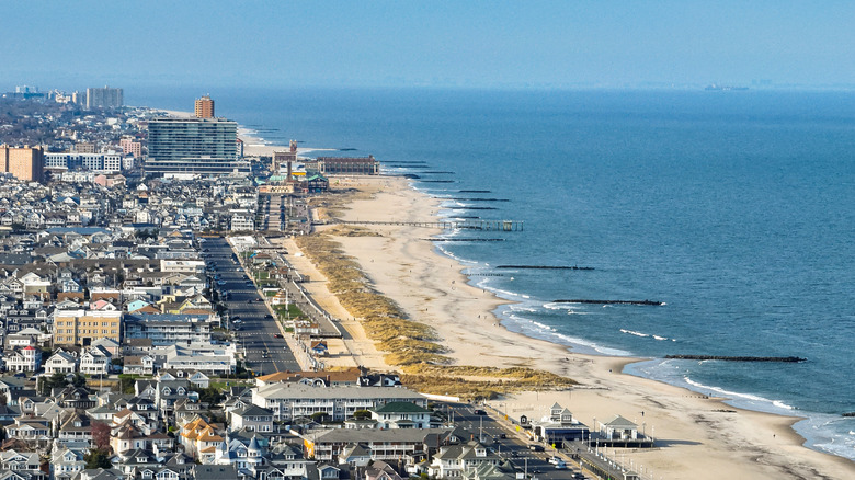 Aerial view of Monmouth Beach, with buildings on the left and the ocean on the right, under a blue sky