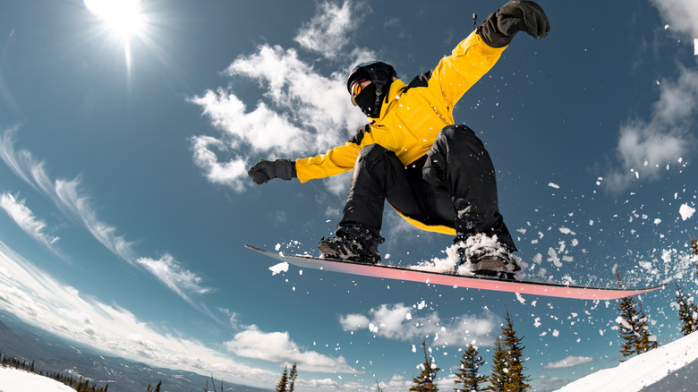 snowboarder wearing a yellow jacket going over a jump