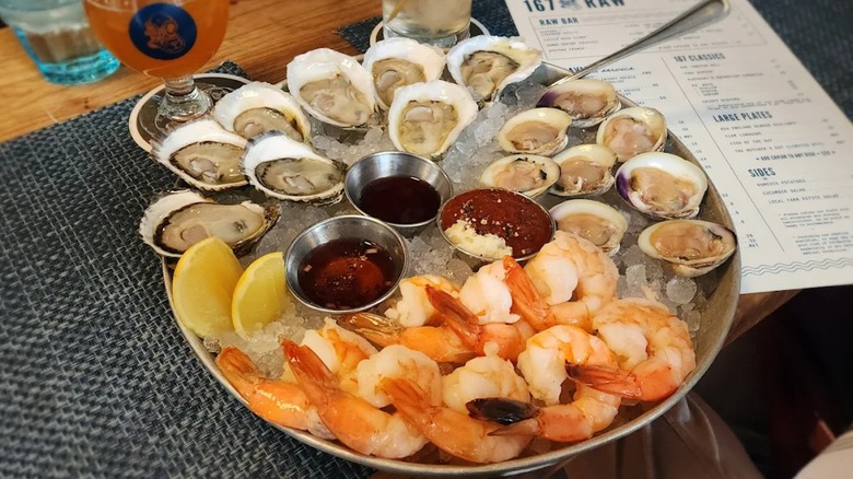 An oyster and shrimp bowl on ice with sauces and lemon