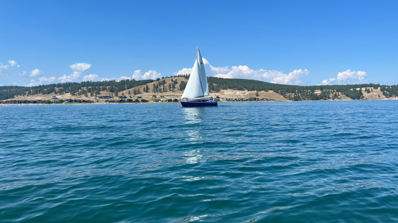 A close-up shot of Lake Koocanusa blue waters, with a sailboat in distance