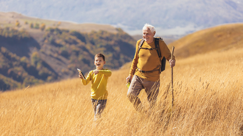 Senior with young boy hiking on a hill