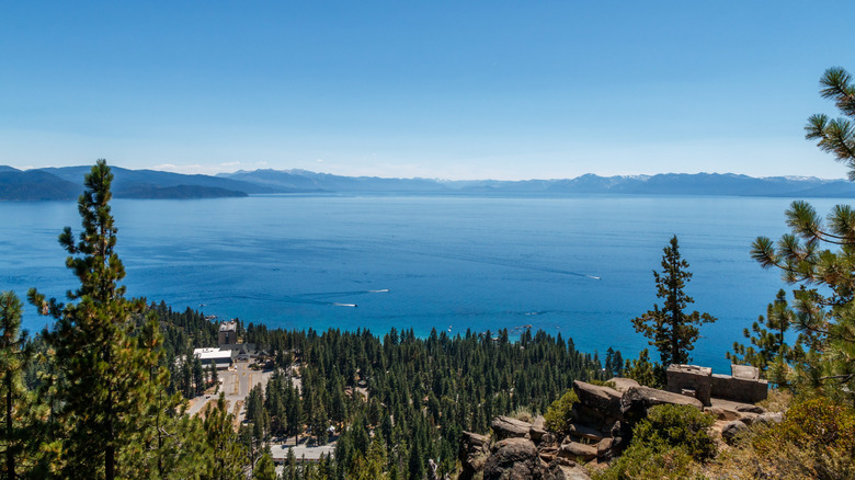 A rocky ledge overlooks Kings Beach and Lake Tahoe at the North Shore as boats zigzag on the turquoise waters.