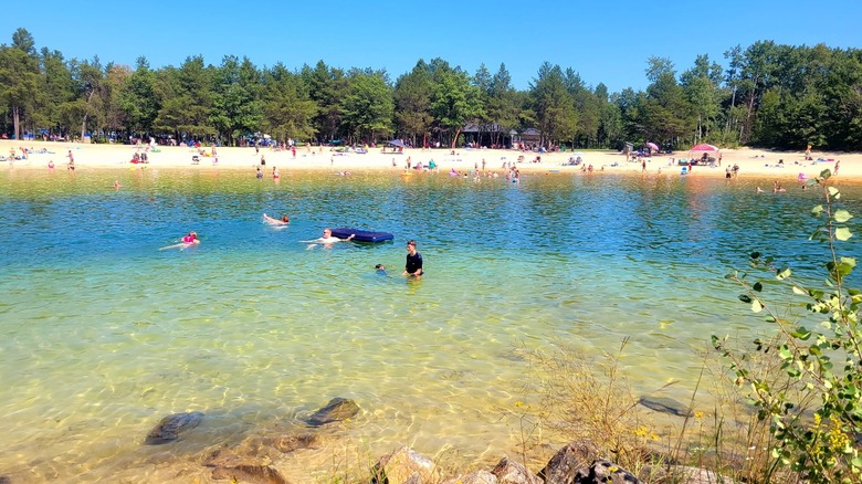 People swimming and floating in the shallow waters of Wazee Lake beach