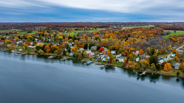 A village along the shore of a lake with old buildings, docks, and fall foliage