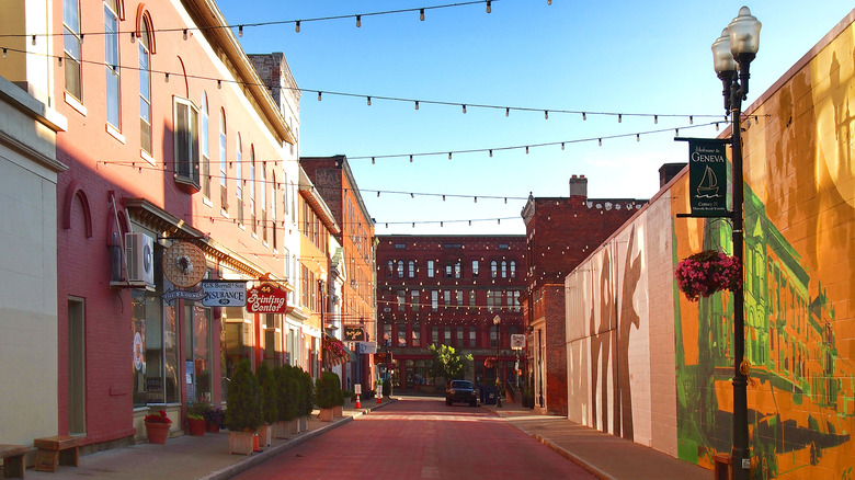 A shopping street lined with crisscrossing string lighting and murals along one side of the street