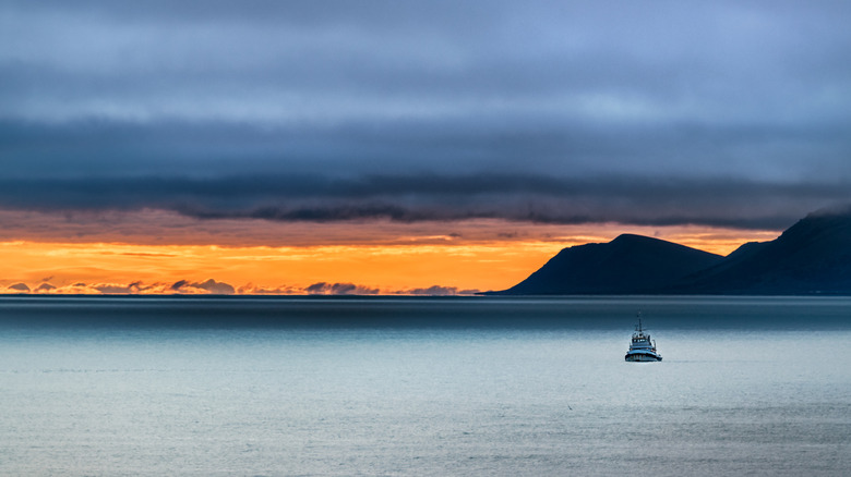Scenery of a small ship on the Bering sea and the St Lawrence island in the background