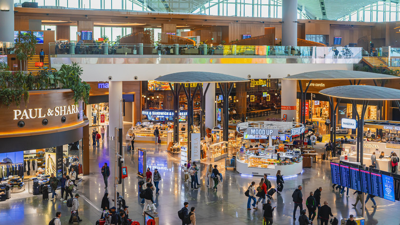 Vibrant shopping area with travelers and bright neon lights in the departure terminal at Istanbul Airport, Turkey