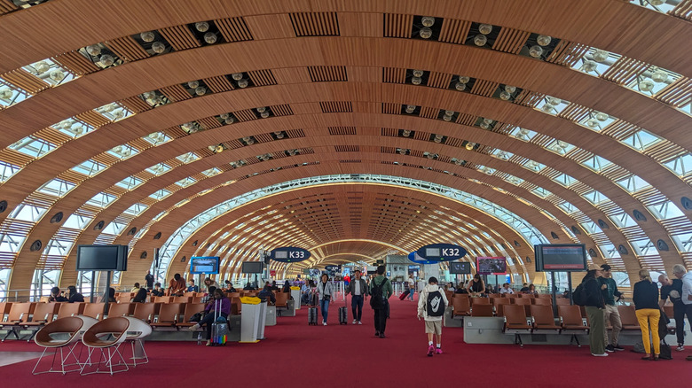 Passengers sitting on chairs and waiting for their flights at Aeroport de Paris-Charles de Gaulle