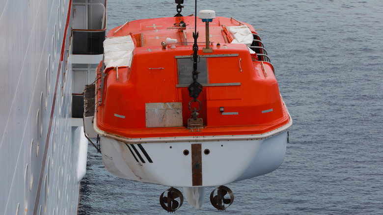 A lifeboat being winched from the side of a ship