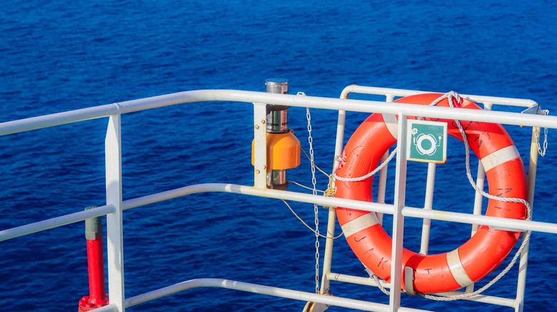 Bright orange ring shaped rescue life buoy installed on a ship's rail, stand by for man overboard.