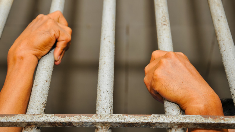Prisoner's hands behind bars