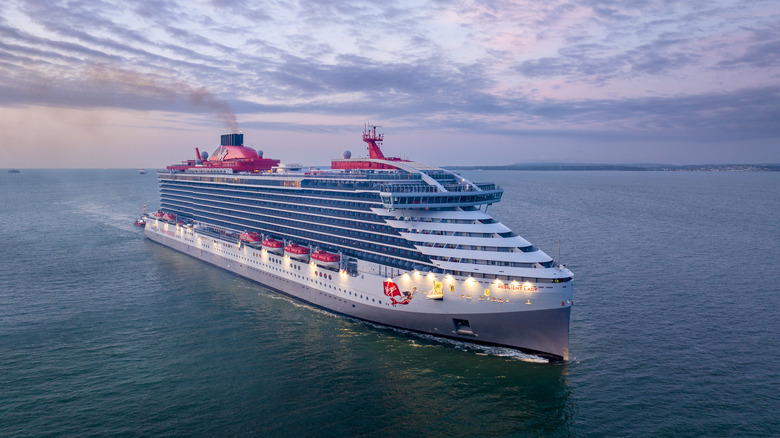 Virgin Voyages' Resilient Lady cruise ship sailing in open water at dusk