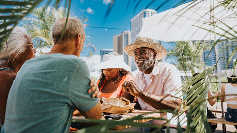Two happy retiree couples enjoying a meal at an outdoor eatery in Honolulu
