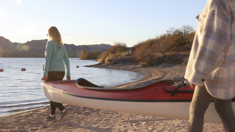 People carrying kayak out to water's edge