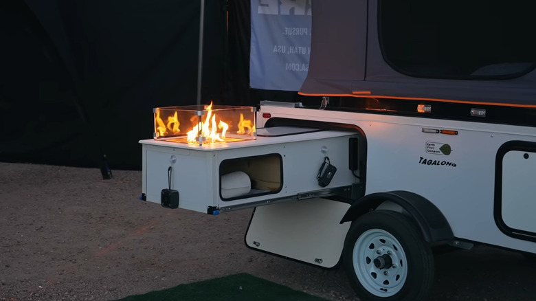 A portable fire pit in a pullout compartment of a camping trailer