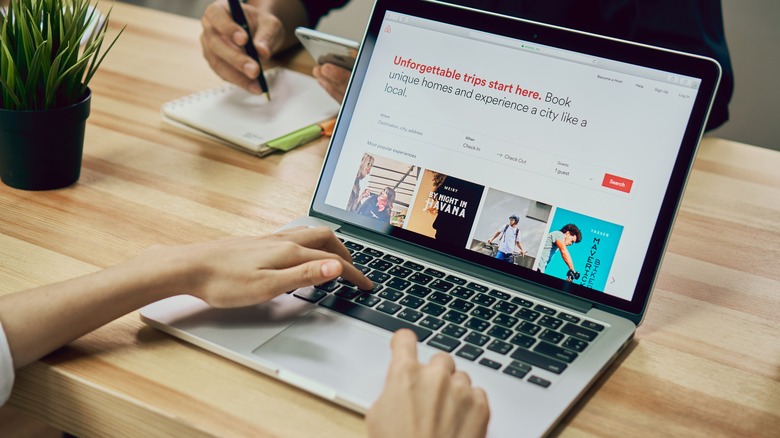 Person looks at Airbnb landing page on open laptop