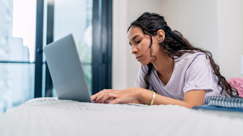 Young woman in bed on her laptop