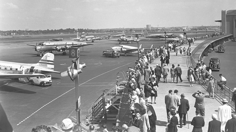 People walking on an outdoor walkway at the airport in the 1960s
