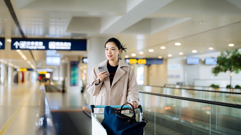 Smiling woman pushing a luggage cart at the airport
