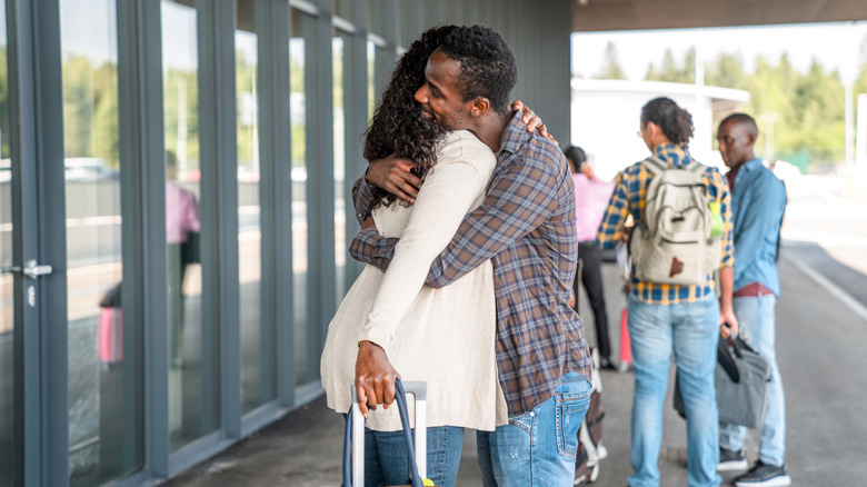 People hugging outside an airport while saying goodbye
