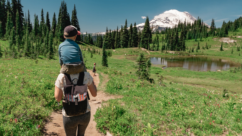 A young mother carrying son toward Mt Rainier on the Naches Peak Loop Trail in Mt. Rainier National Park.