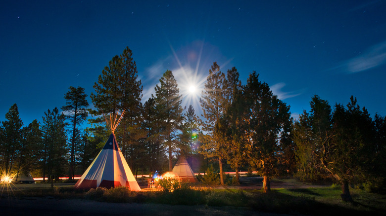 A teepee illuminated by a bonfire and moonlight at Bryce Canyon National Park in Utah
